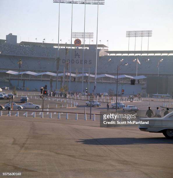 Exterior view of Dodger Stadium, as seen across a mostly empty parking lot, Los Angeles, California, August 1963.