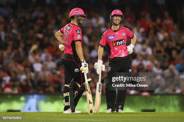 Moises Henriques of the Sixers and Jordan Silk of the Sixers talk between overs during the Big Bash League match between the Melbourne Renegades and...