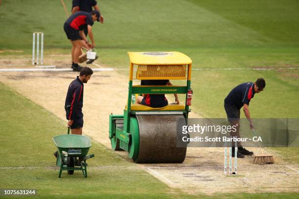 The groundsmen prepare the pitch during a break during day four of the Third Test match in the series between Australia and India at Melbourne...