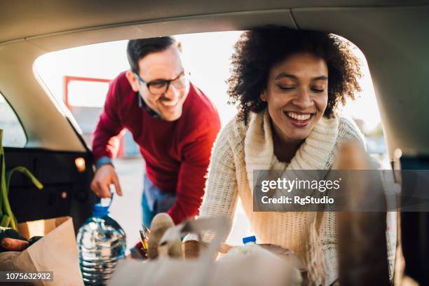 woman putting groceries in a car - car trunk stock pictures, royalty-free photos & images