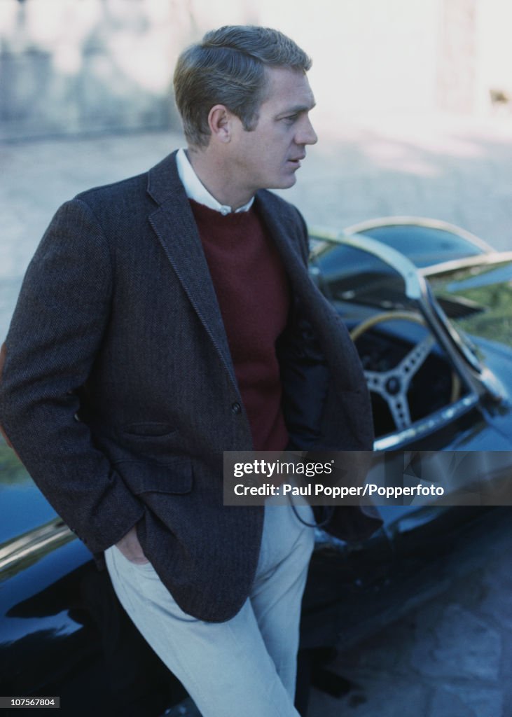 American actor Steve McQueen leaning on his Jaguar D-Type XKSS sports
