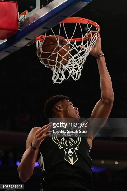 Giannis Antetokounmpo of the Milwaukee Bucks hangs on to the hoop after making a basket during the fourth quarter of the game against New York Knicks...