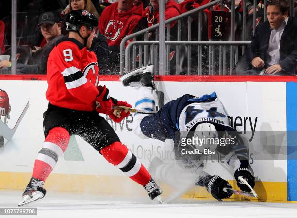 Taylor Hall of the New Jersey Devils checks Josh Morrissey of the Winnipeg Jets in the overtime period at Prudential Center on December 01, 2018 in...