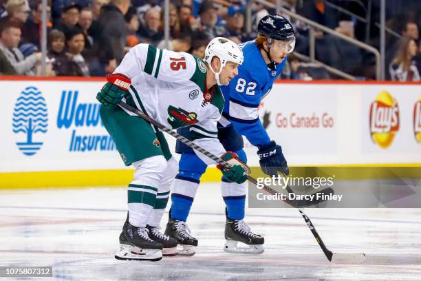 Matt Hendricks of the Minnesota Wild and Mason Appleton of the Winnipeg Jets get set for a second period face-off at the Bell MTS Place on December...