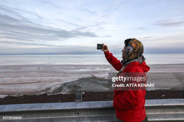 An Iranian journalist uses her phone to take a picture of the salt lake of Urmia in the country's northwest, which had been shrinking in one of the...