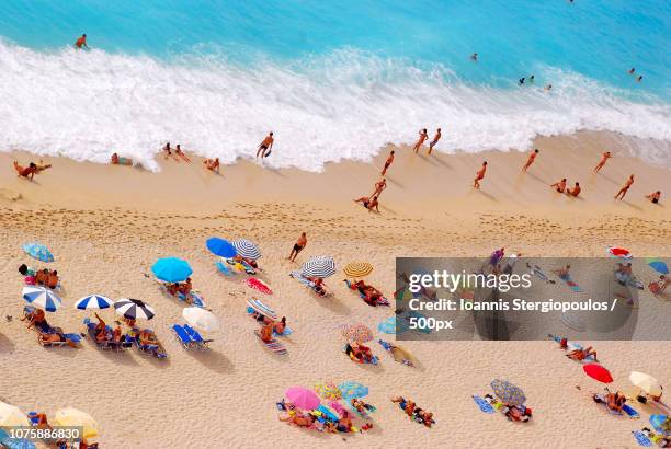 people sunbathing on egremni beach in lefkada - egremni stock pictures, royalty-free photos & images