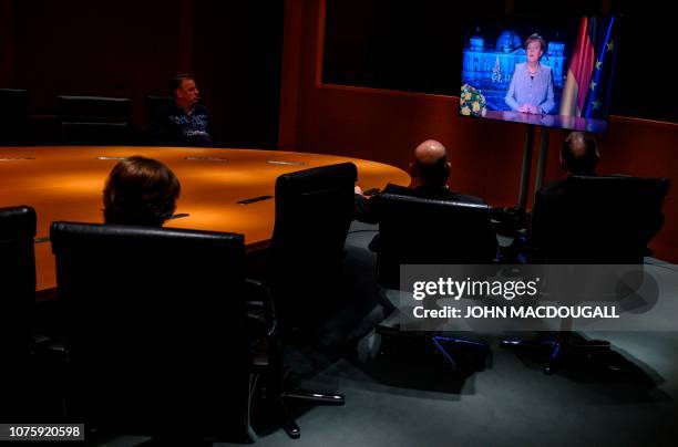 Chancellery officials and media technicians watch a monitor showing German Chancellor Angela Merkel as she delivers her annual New Year's speech in...