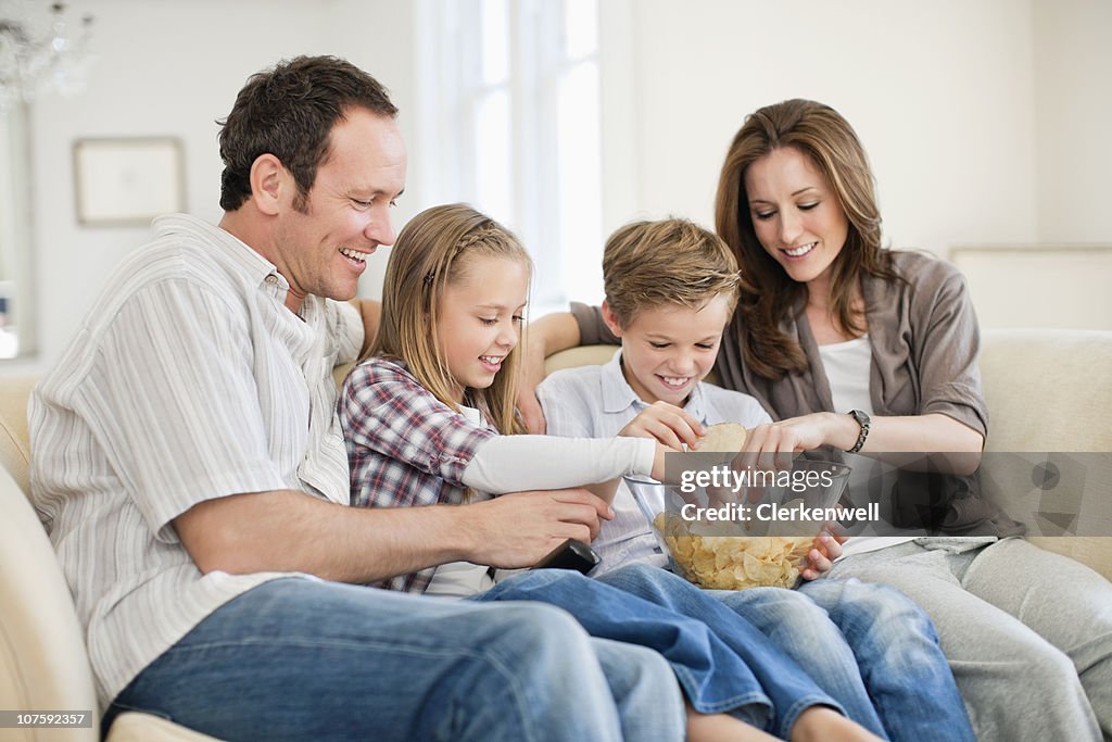 Couple with kids (8-11) having chips at home