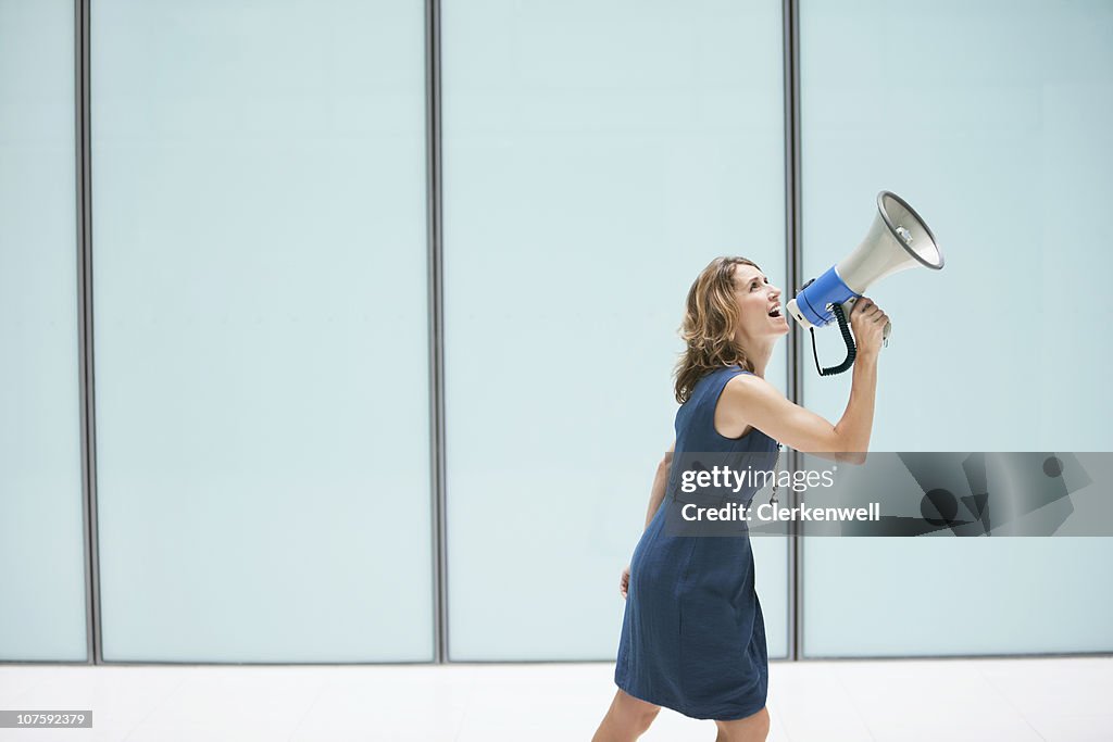 Woman shouting through megaphone at office lobby