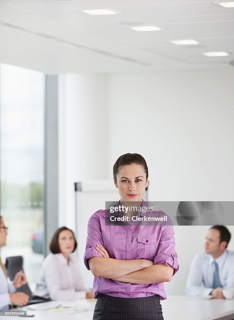 Portrait of confident businesswoman with executives in the background