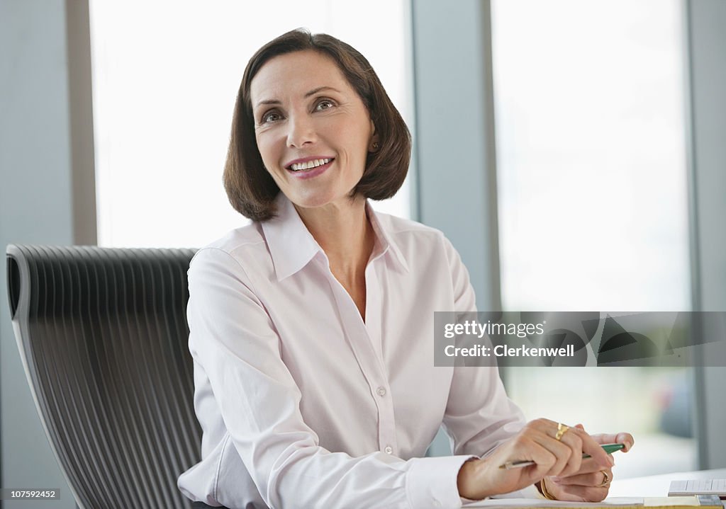 Caucasien femme regardant loin tout en elle assis dans le bureau