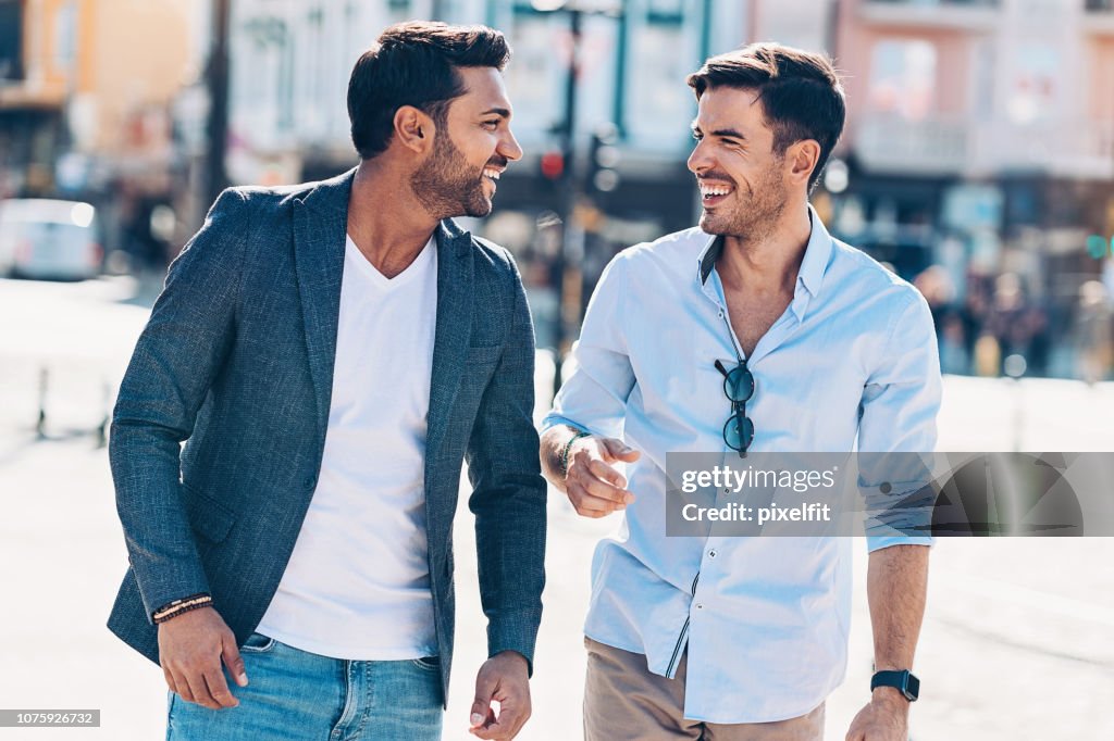 Two smiling men walking together and talking
