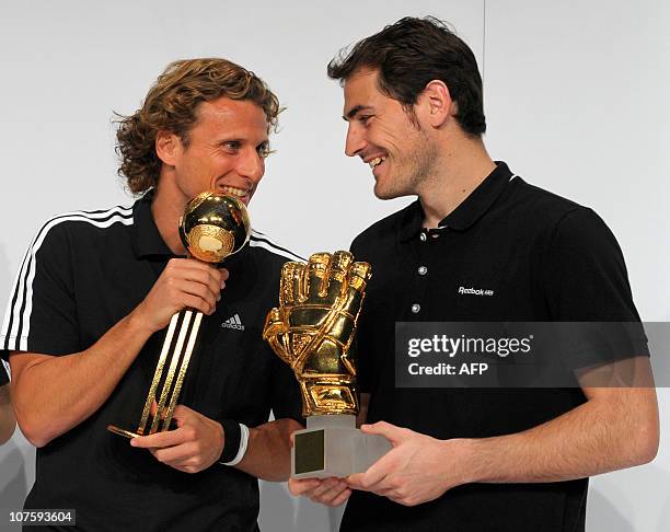 Golden Ball winner Uruguay's striker Diego Forlan and Golden Glove winner Spain's goalkeeper Iker Casillas joke with their awards during the FIFA...