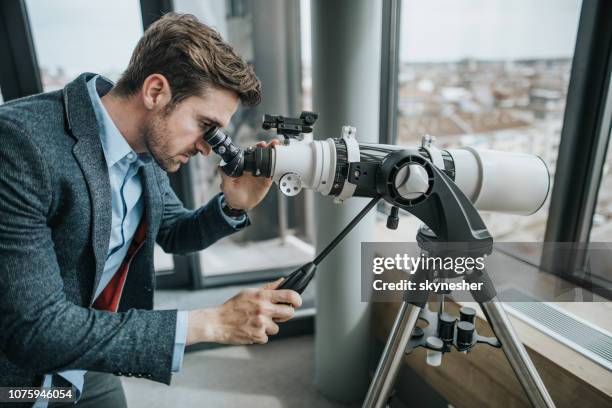 young businessman looking through a telescope. - looking through an object stock pictures, royalty-free photos & images