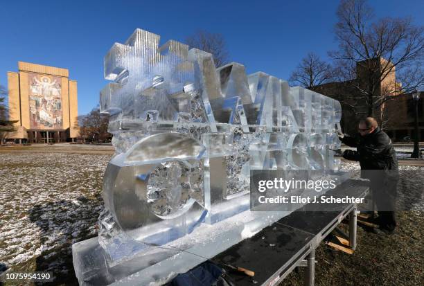 Ice sculpture artist Josh Hummel works on his piece ahead of the 2019 Bridgestone Winter Classic in front of the The Word of Life Mural on December...