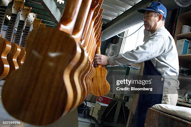 An employee works on ukuleles at the Mitsuba Gakki Co. Factory in Maebashi City, Gunma Prefecture, Japan, on Tuesday, Dec. 14, 2010. Confidence among...