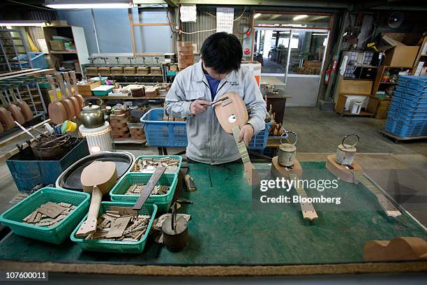 An employee assembles the parts of an ukulele at the Mitsuba Gakki Co. Factory in Maebashi City, Gunma Prefecture, Japan, on Tuesday, Dec. 14, 2010....