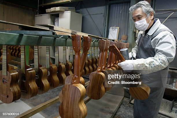 An employee coats an ukulele with varnish at the Mitsuba Gakki Co. Factory in Maebashi City, Gunma Prefecture, Japan, on Tuesday, Dec. 14, 2010....