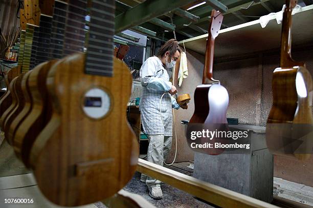 An employee coats an ukulele at the Mitsuba Gakki Co. Factory in Maebashi City, Gunma Prefecture, Japan, on Tuesday, Dec. 14, 2010. Confidence among...