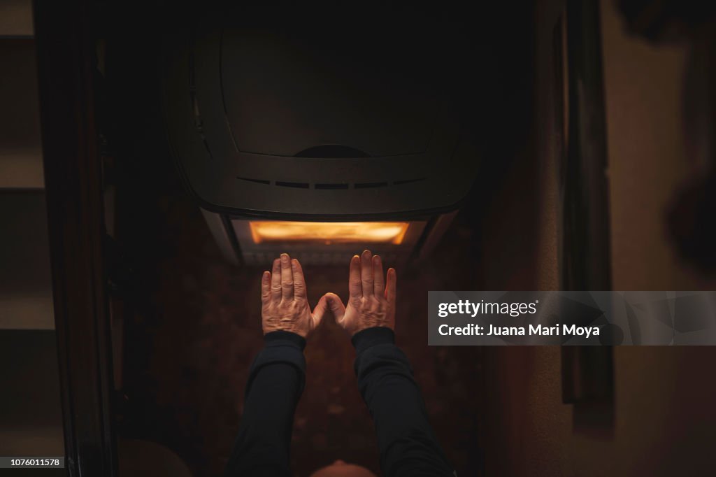 Man's hands warming up on an electric stove