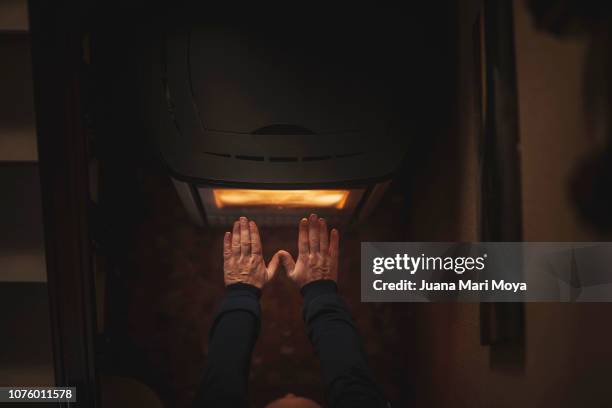 man's hands warming up on an electric stove - cold house stock pictures, royalty-free photos & images