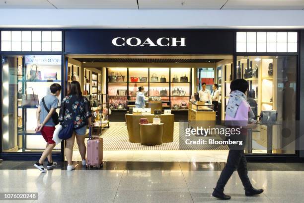 Travelers walk past a Coach Inc. Store at the Tan Son Nhat International Airport in Ho Chi Minh City, Vietnam, on Saturday, Dec. 22, 2018. Vietnam's...