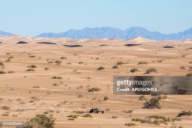 An off-road vehicle drives near the US-Mexico border fence at the Imperial Sand Dunes Recreation Area east of Calexico, California, on December 30,...