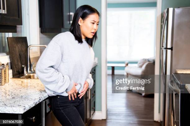 een jonge vrouw bekken ongemak ervaart, is ze grimassen in pijn. - bekken stockfoto's en -beelden
