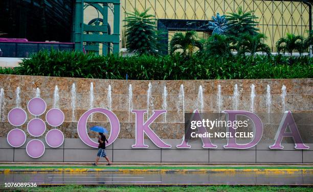 Man walks past the logo of Okada Manila in Manila on December 31, 2018. - A luxury Philippine hotel and casino has called off a world record attempt...