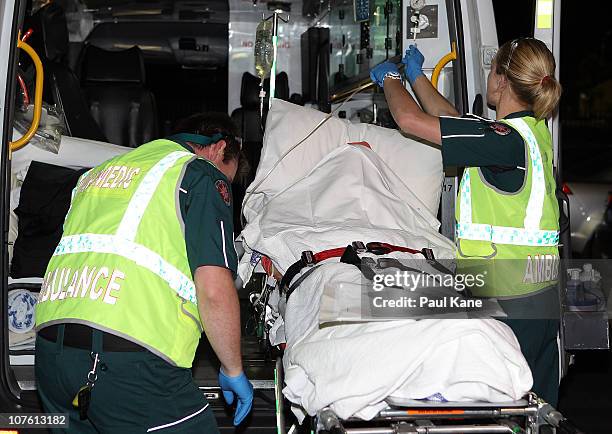 Paramedics load an injured female survivor of the Christmas Island boat wreck into an ambulance after arriving at the Perth Airport on December 16,...