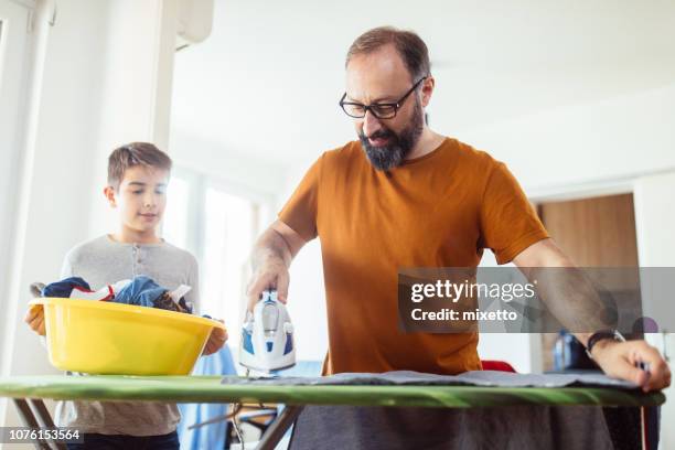 vater mit seinem sohn zu hause bügeln - bügelbrett stock-fotos und bilder