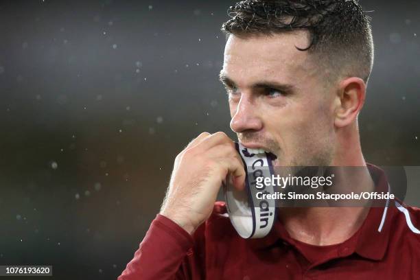 Jordan Henderson of Liverpool holds his captain's armband in his mouth as he removes his shirt after the Premier League match between Wolverhampton...
