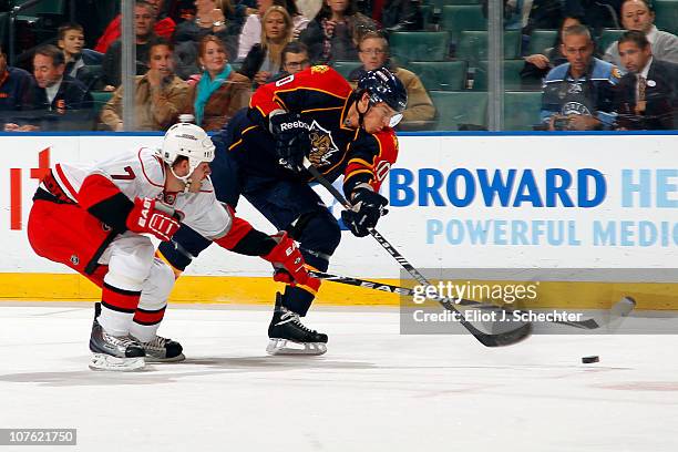 David Booth of the Florida Panthers crosses sticks with Ian White of the Carolina Hurricanes at the BankAtlantic Center on December 15, 2010 in...