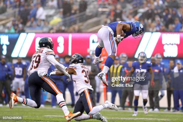 Saquon Barkley of the New York Giants leaps over Adrian Amos of the Chicago Bears for extra yardage during the third quarter at MetLife Stadium on...