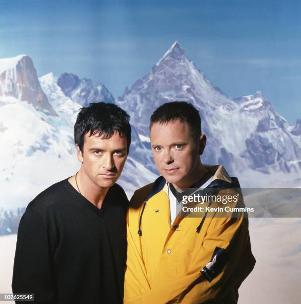 Johnny Marr and Bernard Sumner of British dance music duo Electronic, standing in front of a painted backdrop of an alpine scene, circa 1990.
