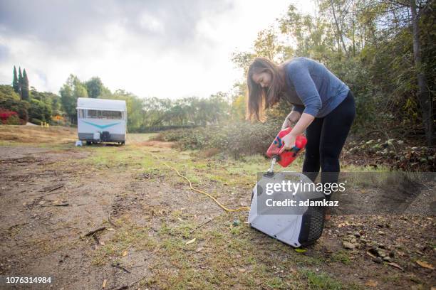 joven mujer vertiendo gas en el generador en el campamento - generator fotografías e imágenes de stock