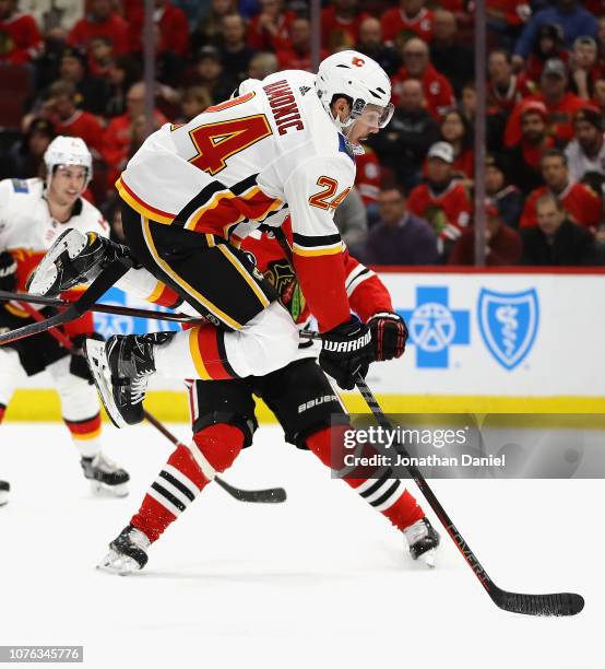 Travis Hamonic of the Calgary Flames leaps out of the way of the puck against the Chicago Blackhawks at the United Center on December 02, 2018 in...