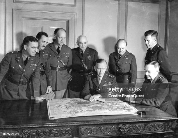 Portrait of American military commander General George C. Marshall as he looks at a map with members of his General Staff in his office at the War...