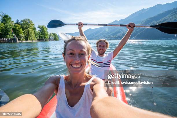 junges paar unter selfie porträt in rote kanu am bergsee - sharing two people stock-fotos und bilder