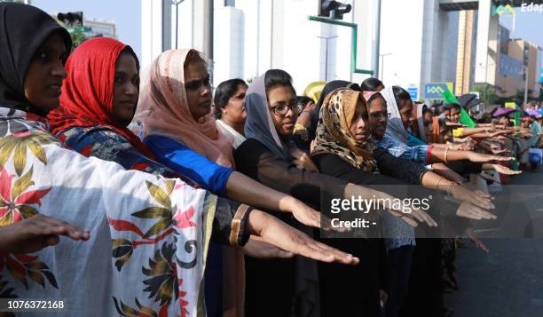 Indian women hold out their hands as they stand in a line to take part in a "women's wall" protest in Kochi in southern Kerala state on January 1,...
