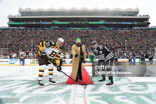 Notre Dame alumni Tim Brown drops the puck for the ceremonial opening face-off between Zdeno Chara of the Boston Bruins and Jonathan Toews of the...