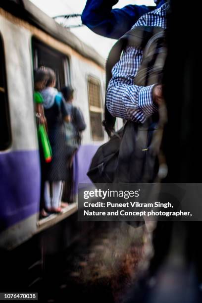 commuters hang on the outside of a local train in mumbai during rush hour - overloaded passenger trains in india stock pictures, royalty-free photos & images