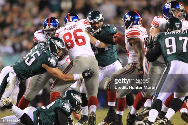 Linebacker Stewart Bradley and defensive end Darryl Tapp of the Philadelphia Eagles tackle tight end Bear Pascoe of the New York Giants during a game...