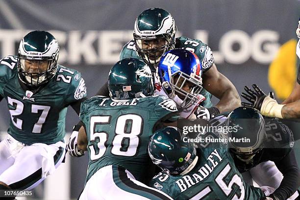 Linebacker Stewart Bradley, defensive end Trent Cole and linebacker Moise Fokou of the Philadelphia Eagles tackle running back Ahmad Bradshaw of the...