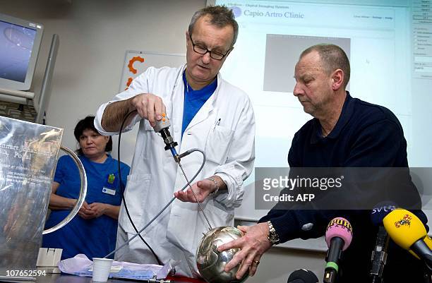 Former national soccer team physician Magnus Forsblad and Christer Rohman of the Swedish football league use an arthroscope to look inside the...