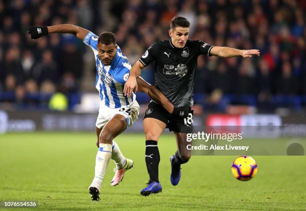 Steve Mounie of Huddersfield Town and Ashley Westwood of Burnley clash during the Premier League match between Huddersfield Town and Burnley FC at...