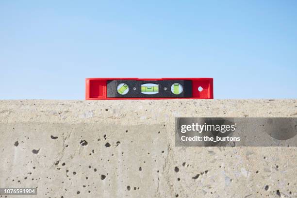 still life of red spirit level on concrete wall against blue sky - bilancia strumento foto e immagini stock