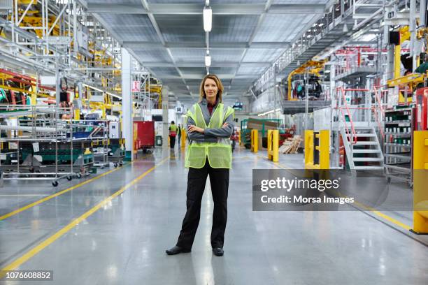 mature female supervisor with arms crossed - factory engineer woman imagens e fotografias de stock