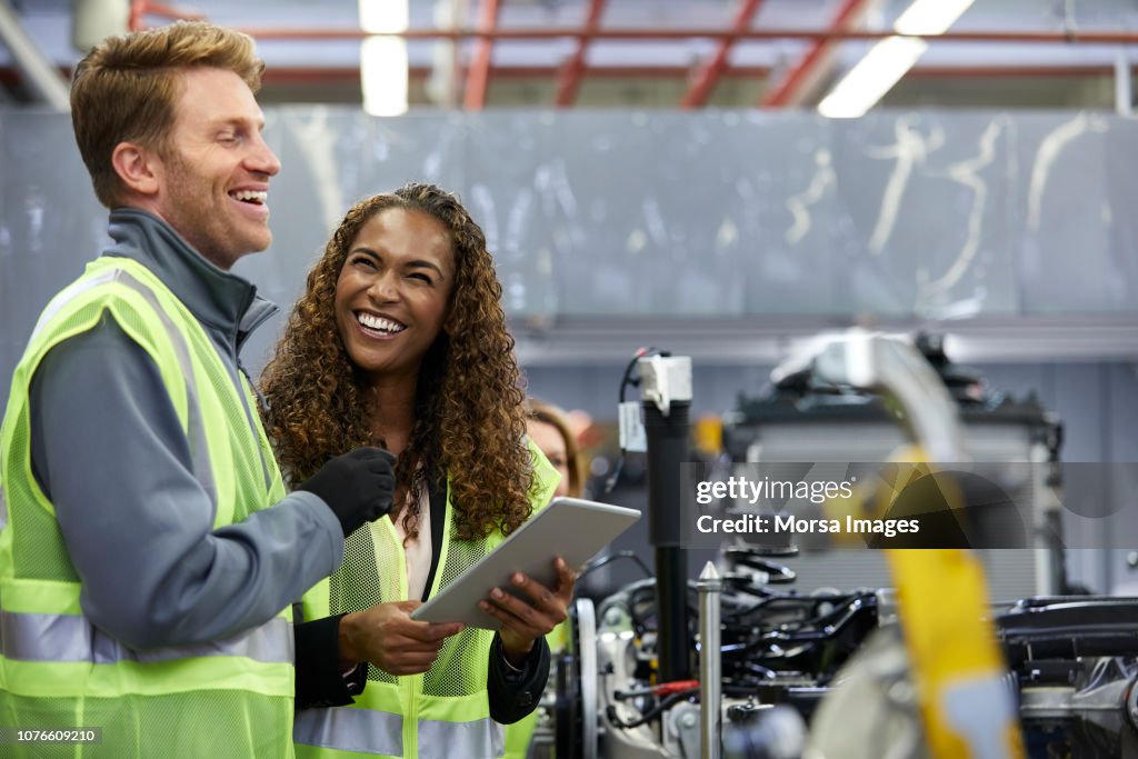 Smiling engineers standing with digital tablet