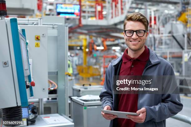 ingegnere maschio che tiene tablet pc in un impianto automobilistico - engineering foto e immagini stock